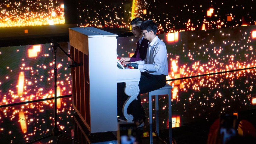 智能仿生手使用者古月與少年鋼琴家舒海峰合奏。主辦方供圖